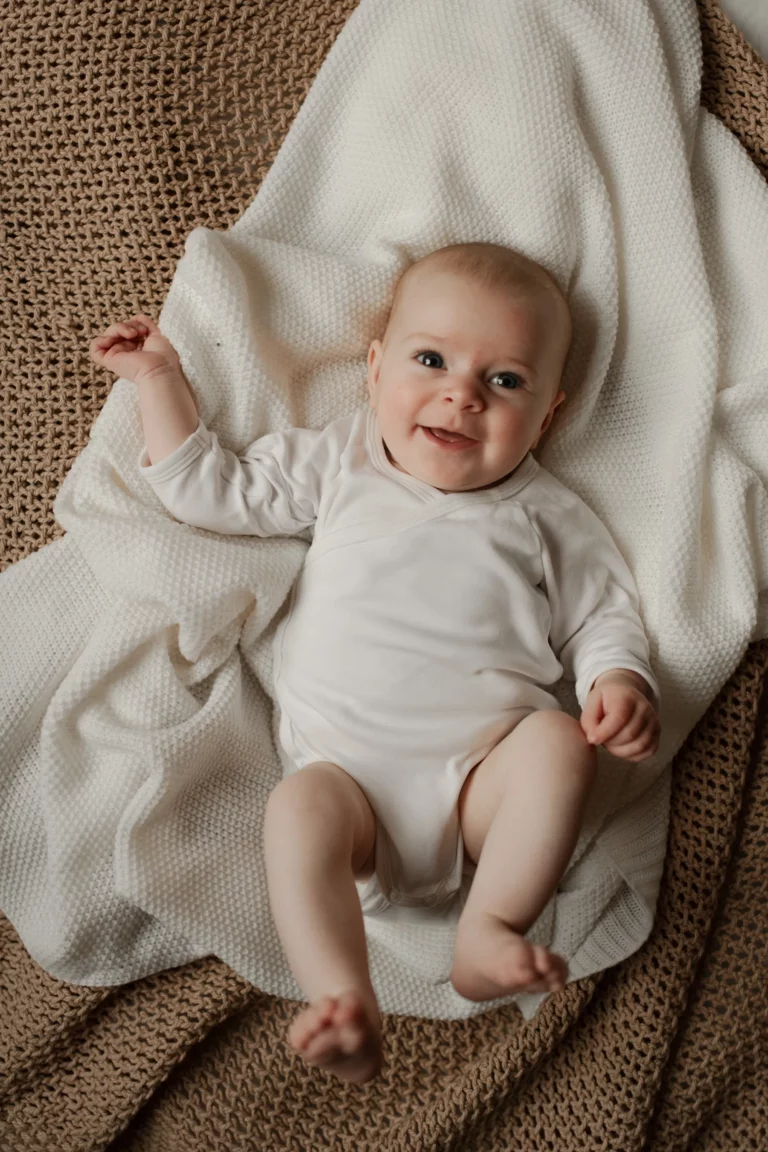 Bébé allongé sur le lit des parents – séance photo naissance en lumière naturelle.