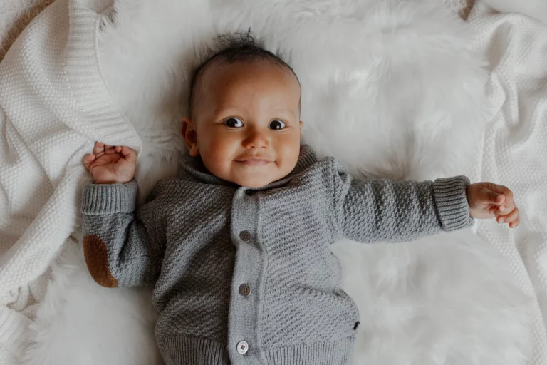 Bébé allongé sur une couverture beige – séance photo naissance en intérieur.