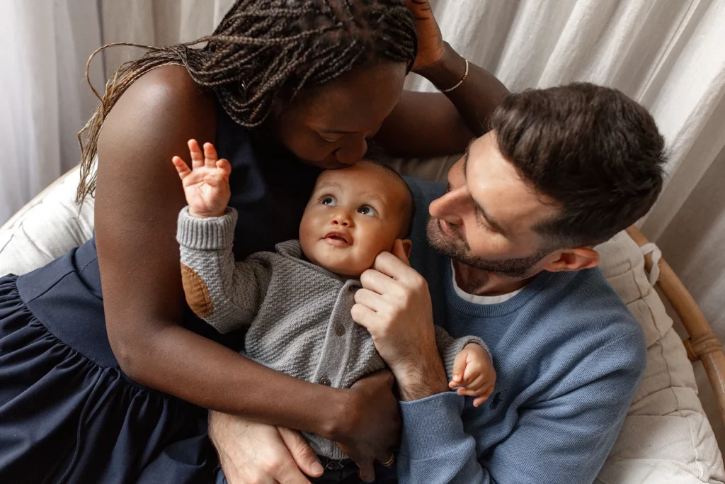 Gros plan sur le bébé dans les bras de ses parents dans le fauteuil du studio