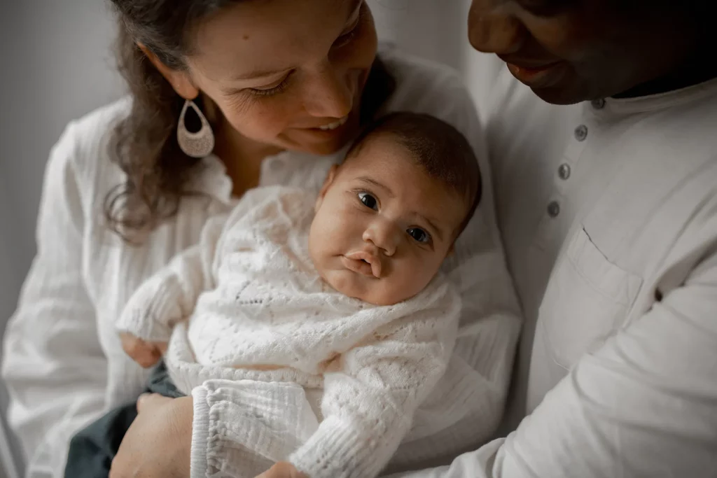 Photo de famille en studio – nouveau-né dans les bras de ses parents.